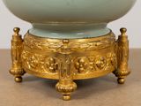 a gold and green bowl on a stand on a table