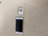 a white cell phone sitting on a table next to a charger