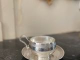 une tasse et une soucoupe argentées posées sur une table noire