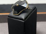 une bague noire et dorée posée sur un coffret noir
