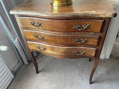 a small wooden chest of drawers with a vase on top of it
