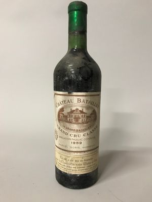 une vieille bouteille de vin posée sur une table blanche