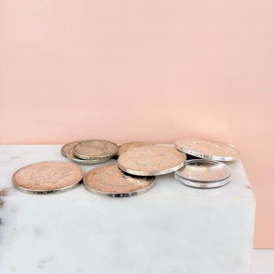 coins are sitting on top of a marble block on a pink background