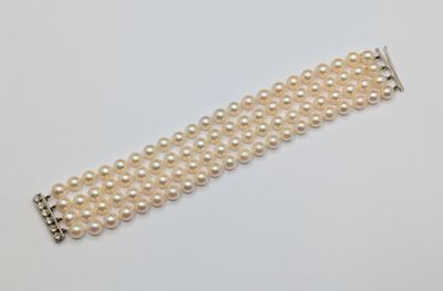 un gros plan d'un bracelet de perles blanches posé sur une surface blanche