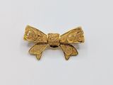 an image of a gold bow brooch on a white background