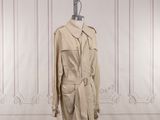 un trench-coat beige posé sur un mannequin dans une pièce blanche