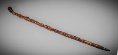 an old wooden stick with a carved handle on a gray background