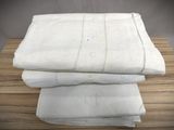 three white linens stacked on top of each other on a wooden table