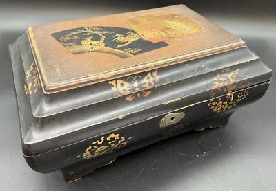 une boîte noire et dorée posée sur une table, sur fond noir
