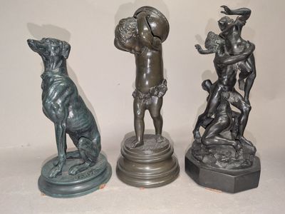 trois statues en bronze représentant un homme et un chien, posées sur un socle