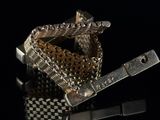 a silver and gold bracelet with a clasp on a black surface