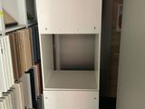a tall white cabinet with a shelf in the middle of a room