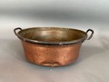 an old copper pot with handles on a white surface