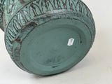 a green vase sitting on a white surface