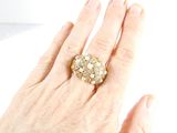 a woman ' s hand holding a gold ring with pearls on it