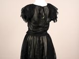 une robe noire posée sur un présentoir à mannequin, avec un collier autour du cou