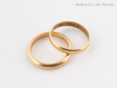 two gold wedding rings sitting on top of each other on a white surface