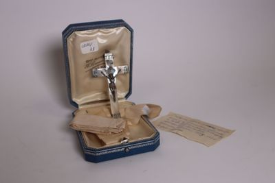 un petit crucifix en argent dans un écrin bleu
