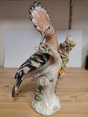a figurine of a bird sitting on a tree branch