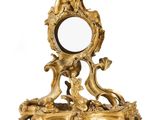 un miroir doré richement décoré, surmonté d'un oiseau