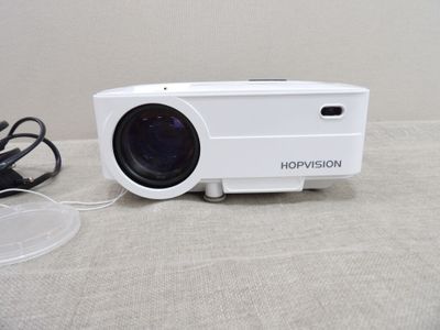 un projecteur blanc posé sur une table à côté d'un chargeur