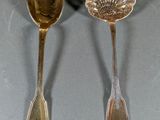 two spoons and a spoon rest on a table with a shadow on the table