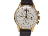 un gros plan d'une montre dorée et noire sur fond blanc