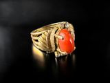 a close up of a gold ring with a red stone