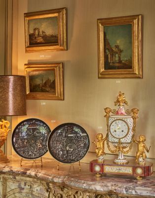 une table avec une horloge, une lampe et des tableaux accrochés au mur