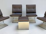 trois fauteuils en cuir marron et une petite table dans une pièce blanche