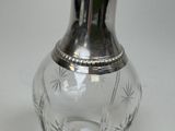 a glass vase with a silver lid sitting on a table