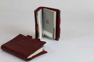 un portefeuille posé sur une surface blanche, à côté d'un livre ouvert, sur fond blanc