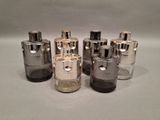 four different sizes of silver and black glass bottles on a white surface