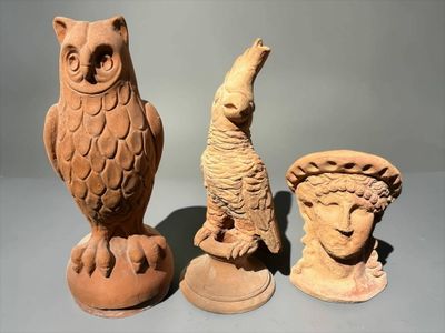 three clay figurines of animals and a bird on display