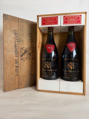 two bottles of wine are in a wooden box on a white surface