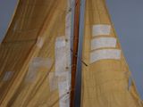 a sail boat with a yellow sail on the water