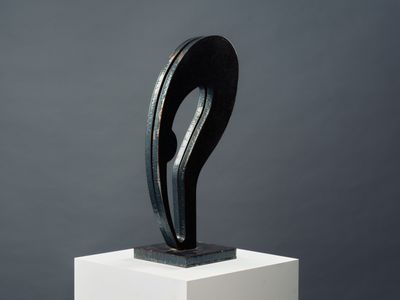une sculpture en noir et blanc posée sur un socle, sur fond gris