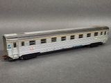 a silver train car that is sitting on a gray surface