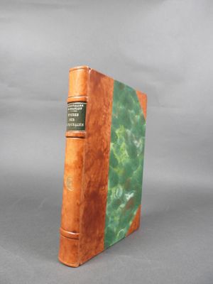 un vieux livre à la couverture verte posé sur une surface grise
