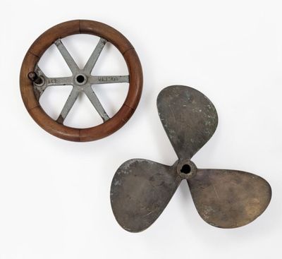 an old propeller and a wooden wheel on a white surface