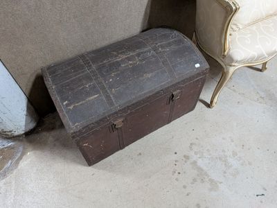 une vieille malle posée à côté d'une chaise dans une pièce