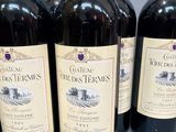 six bottles of red wine are lined up on a table
