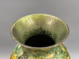 un vase vert et jaune posé sur une table