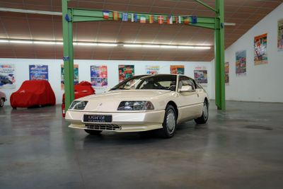 une voiture blanche garée dans un garage, avec d'autres voitures en arrière-plan