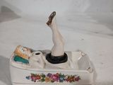 une figurine représentant une femme dans un bateau, posée sur une surface blanche