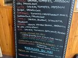 a chalk board with a menu on it in front of a wooden wall