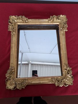un miroir accroché au mur, devant lequel une personne prend une photo