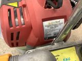 a red blower sitting on the ground next to a tool
