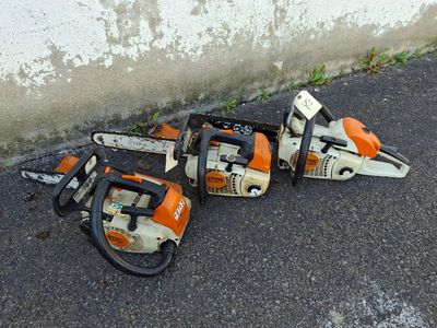 two chainsaws sitting on the ground next to a wall