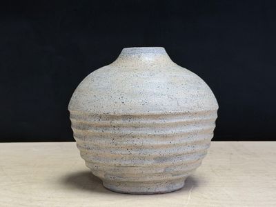 a white vase sitting on a table with a black background